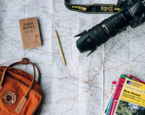 A bag for a happy retirement, Ordnance Survey maps, a Nikon camera, a pencil, and a notebook are scattered on top of an open map.